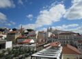Beautiful cityscape of Lisbon showcasing historic architecture and iconic rooftops under a vibrant blue sky.