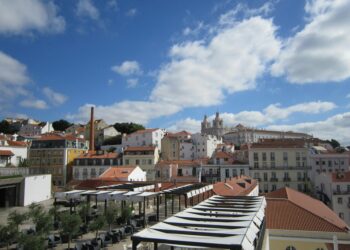 Beautiful cityscape of Lisbon showcasing historic architecture and iconic rooftops under a vibrant blue sky.