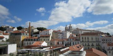 Beautiful cityscape of Lisbon showcasing historic architecture and iconic rooftops under a vibrant blue sky.