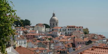 Beautiful view of Lisbon's traditional red rooftops with a prominent dome in the background.