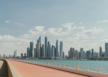 Beautiful view of Dubai Marina's skyscrapers along a sunny waterfront promenade.
