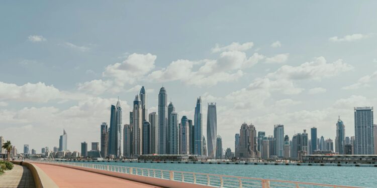 Beautiful view of Dubai Marina's skyscrapers along a sunny waterfront promenade.