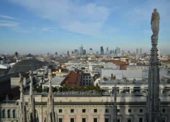 Captivating aerial view of Milan's skyline from atop the Duomo with a clear blue sky backdrop.