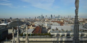 Captivating aerial view of Milan's skyline from atop the Duomo with a clear blue sky backdrop.