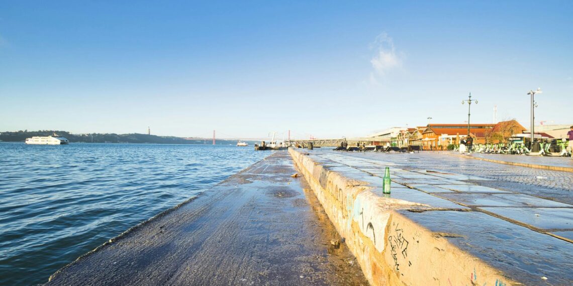 Bright waterfront scene with clear sky and boats in Lisbon, Portugal.