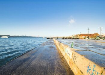 Bright waterfront scene with clear sky and boats in Lisbon, Portugal.