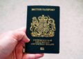 British Passport Second Passport: Rules for Dual Nationals and HNW Travellers — High angle crop anonymous person showing national British passport against blurred gray ground