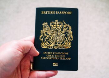 British Passport Second Passport: Rules for Dual Nationals and HNW Travellers — High angle crop anonymous person showing national British passport against blurred gray ground