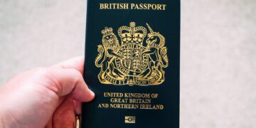 British Passport Second Passport: Rules for Dual Nationals and HNW Travellers — High angle crop anonymous person showing national British passport against blurred gray ground
