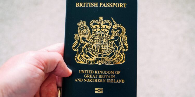 British Passport Second Passport: Rules for Dual Nationals and HNW Travellers — High angle crop anonymous person showing national British passport against blurred gray ground
