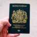 British Passport Second Passport: Rules for Dual Nationals and HNW Travellers — High angle crop anonymous person showing national British passport against blurred gray ground