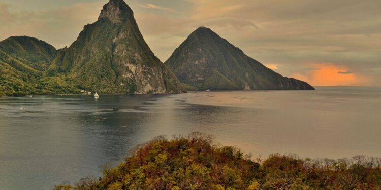 Citizenship by Investment St Lucia: 2026 Complete Programme Guide — A breathtaking sunset view of the Pitons in St. Lucia with lush greenery and calm sea.