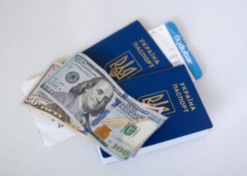 Apply for Second Passport: Same-Country Duplicates vs Citizenship Acquisition — Close-up view of Ukrainian passports with US dollar bills, symbolizing travel readiness.