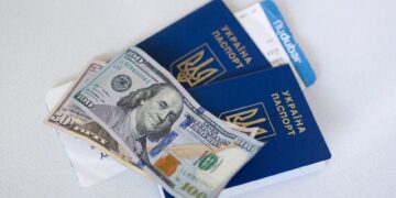 Apply for Second Passport: Same-Country Duplicates vs Citizenship Acquisition — Close-up view of Ukrainian passports with US dollar bills, symbolizing travel readiness.