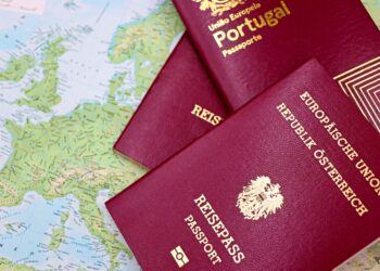 Applying for a Second Passport: Rules, Timelines and Documentation — Close-up of European passports from Portugal and Austria on a world map.