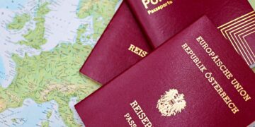 Applying for a Second Passport: Rules, Timelines and Documentation — Close-up of European passports from Portugal and Austria on a world map.