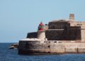 Malta Citizenship by Investment: Why the Programme Closed in 2025 — A striking lighthouse stands by ancient fortifications on the seaside at Valletta, Malta.