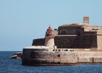 Malta Citizenship by Investment: Why the Programme Closed in 2025 — A striking lighthouse stands by ancient fortifications on the seaside at Valletta, Malta.