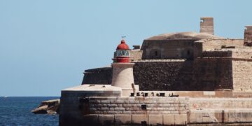 Malta Citizenship by Investment: Why the Programme Closed in 2025 — A striking lighthouse stands by ancient fortifications on the seaside at Valletta, Malta.