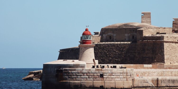 Malta Citizenship by Investment: Why the Programme Closed in 2025 — A striking lighthouse stands by ancient fortifications on the seaside at Valletta, Malta.