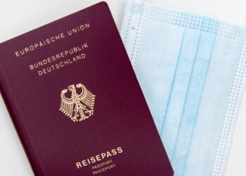 Europe Citizenship by Investment: What Remains After the 2025 CJEU Ruling — Top view of a German passport next to a surgical mask, symbolizing travel during pandemic.