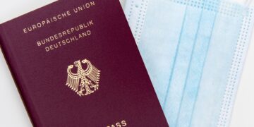Europe Citizenship by Investment: What Remains After the 2025 CJEU Ruling — Top view of a German passport next to a surgical mask, symbolizing travel during pandemic.