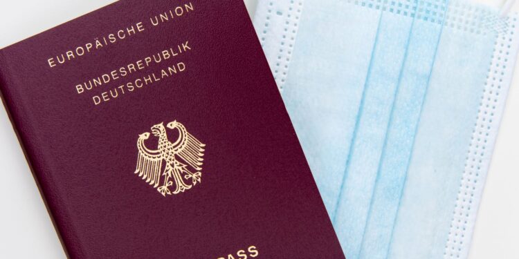 Europe Citizenship by Investment: What Remains After the 2025 CJEU Ruling — Top view of a German passport next to a surgical mask, symbolizing travel during pandemic.