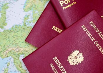 Applying for a Second Passport: Rules, Timelines and Documentation — Close-up of European passports from Portugal and Austria on a world map.
