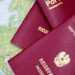 Applying for a Second Passport: Rules, Timelines and Documentation — Close-up of European passports from Portugal and Austria on a world map.