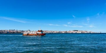 Portugal Golden Visa and Dubai: Dual-Residency Strategy for Wealth Planning — A ferry crossing the Tagus River with Lisbon's scenic skyline in the background.