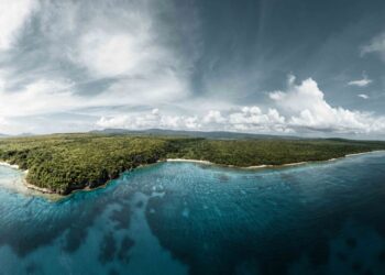 Vanuatu Citizenship by Investment: 2026 Programme Guide — A breathtaking aerial view of the lush green coastline of Vanuatu, surrounded by crystal clear waters.