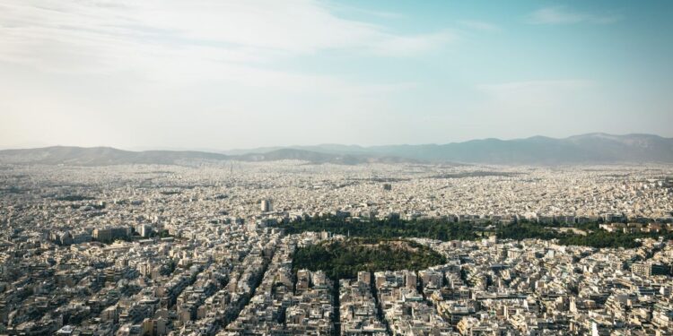 Greece Golden Visa 2026: €250k Property Rules, Tax Residency & Renewal — Aerial view of Athens cityscape showcasing urban density with mountains in the background.